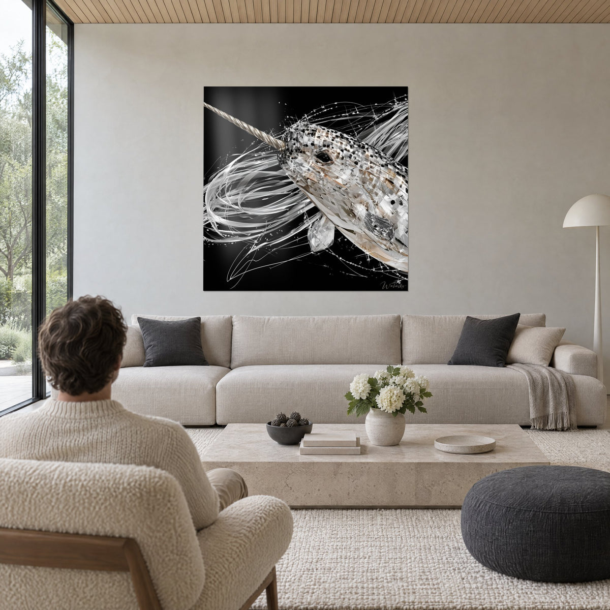 Wall art crystalline narwhal with twisted tusk, silver streaks on black background, man seen from behind, above a sofa in a bright living room