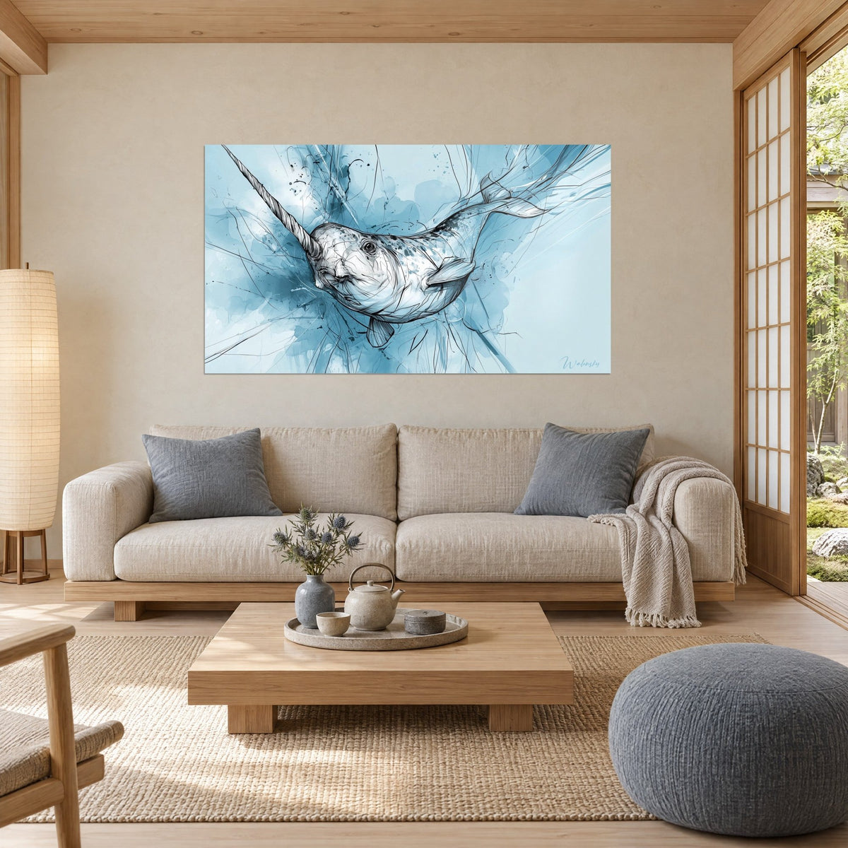 Wall art narwhal with a long spiral tusk, black ink over glacier blue and pearly white washes, above a sofa in a bright living room