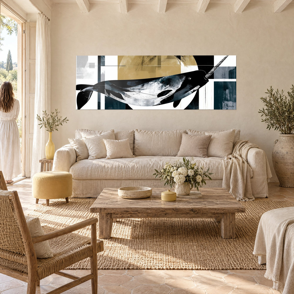 Wall art black narwhal with long striped tusk, ochre disc and petrol blue bands, above a sofa in a bright living room