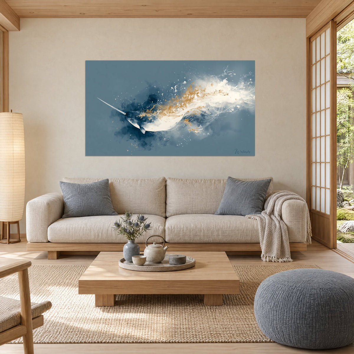 Wall art of a navy blue narwhal with gold splashes, long spiraled tusk and ivory foam, above a sofa in a bright living room