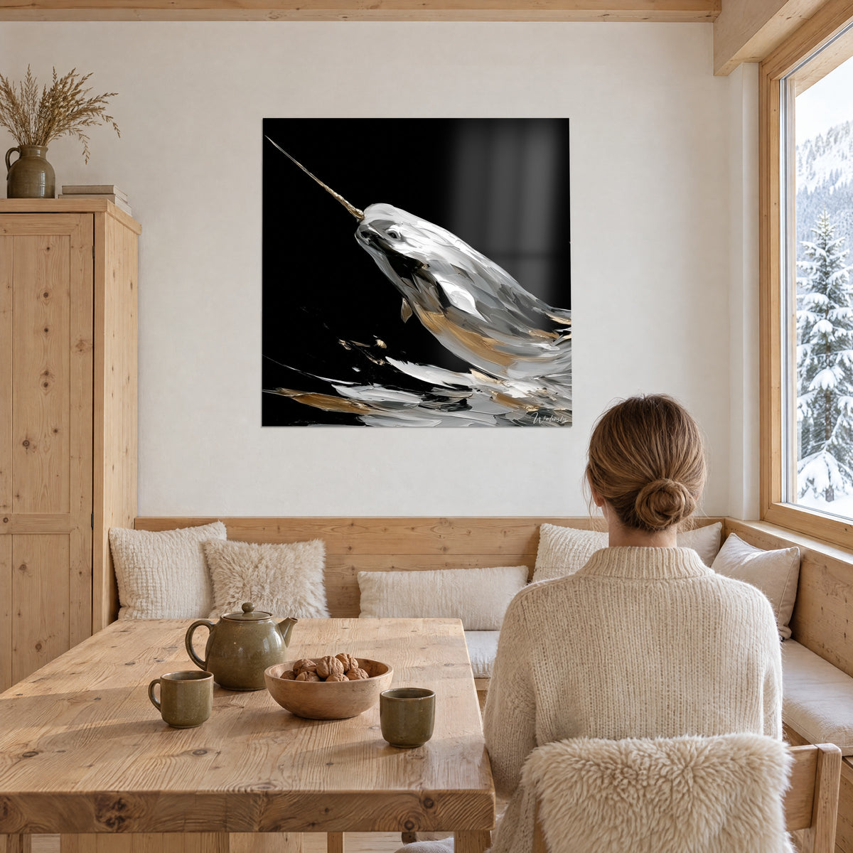 Quadro di un narvalo di profilo con occhio scuro, riflessi grigio argento e dorati su nero, di fronte a un tavolo di legno da chalet
