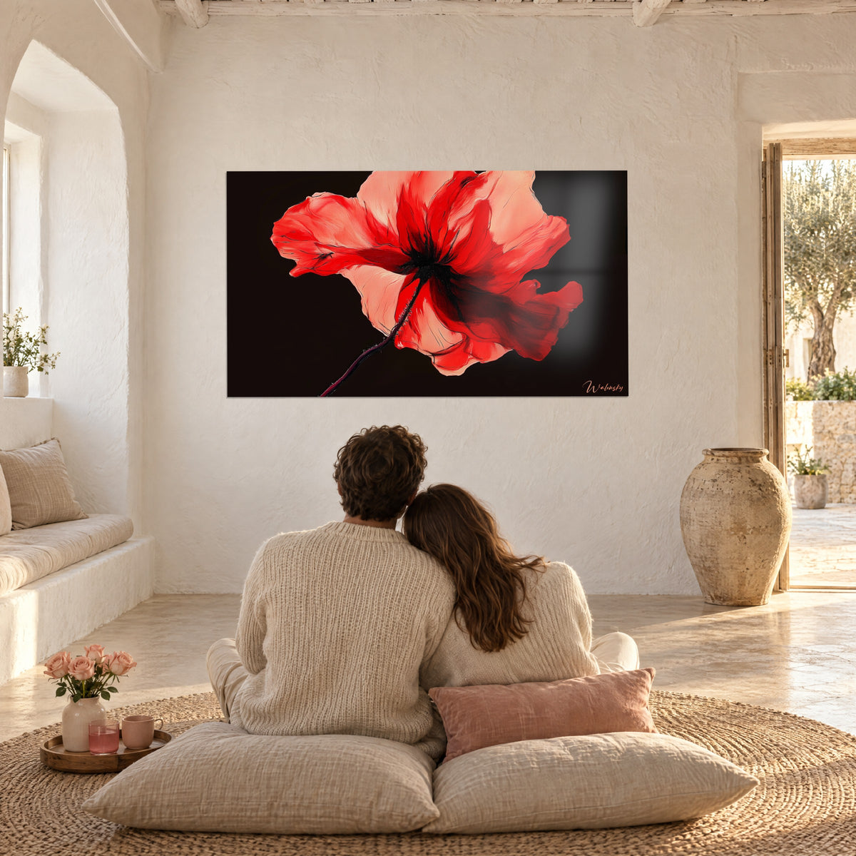 Schilderij met een grote, vlammende klaproos in rood en perzik tegen een zwarte achtergrond, tegenover een stel dat op beige kussens zit