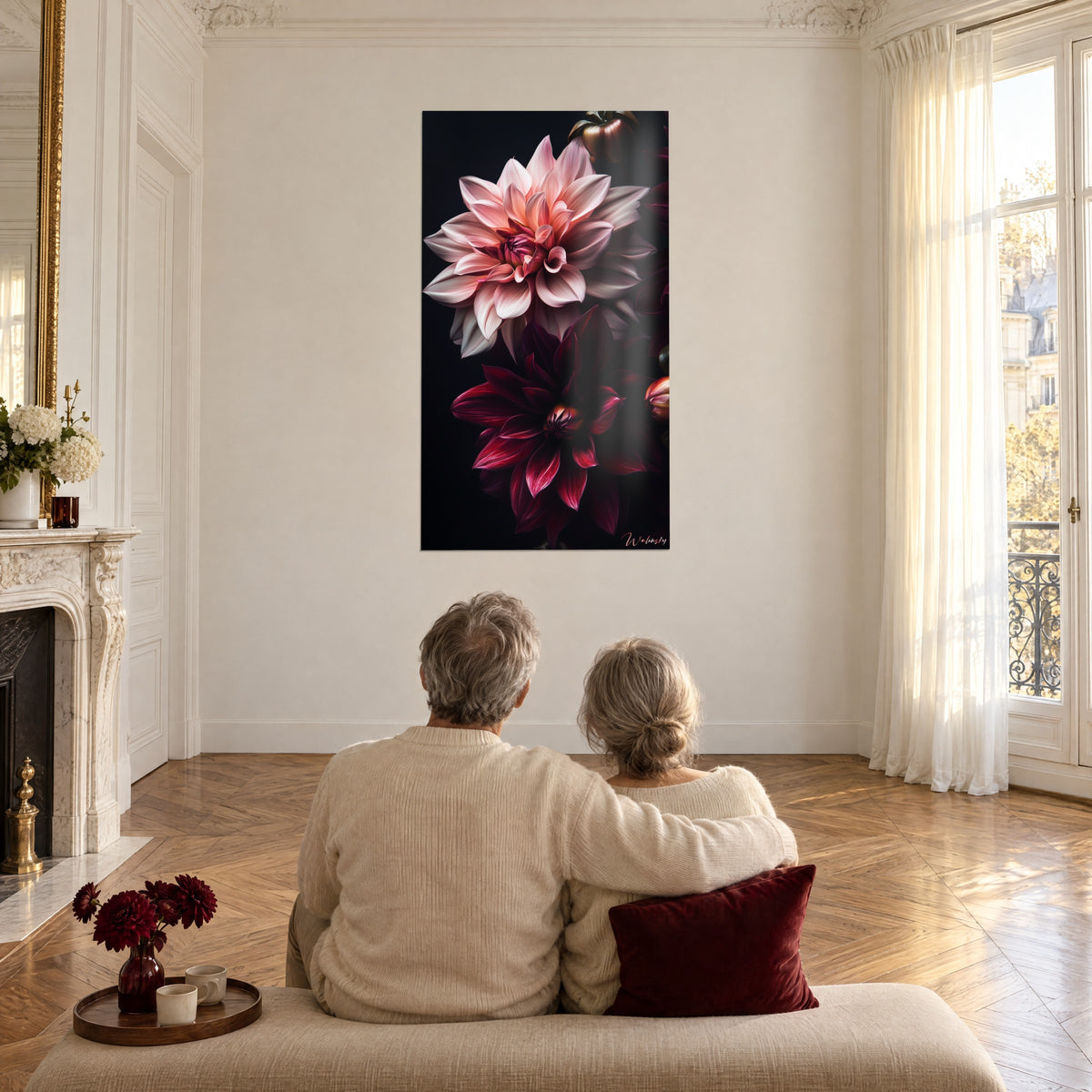 Wall art of large flowers in mother-of-pearl pink and dark plum on a black background, a couple seen from behind seated on a sofa, herringbone parquet floor