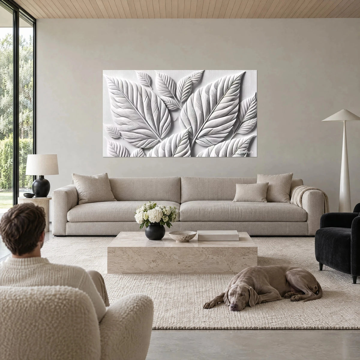Tableau feuilles sculptées en bas-relief, blanc nacré et gris perle, nervures en creux, au-dessus d'un canapé dans un salon lumineux