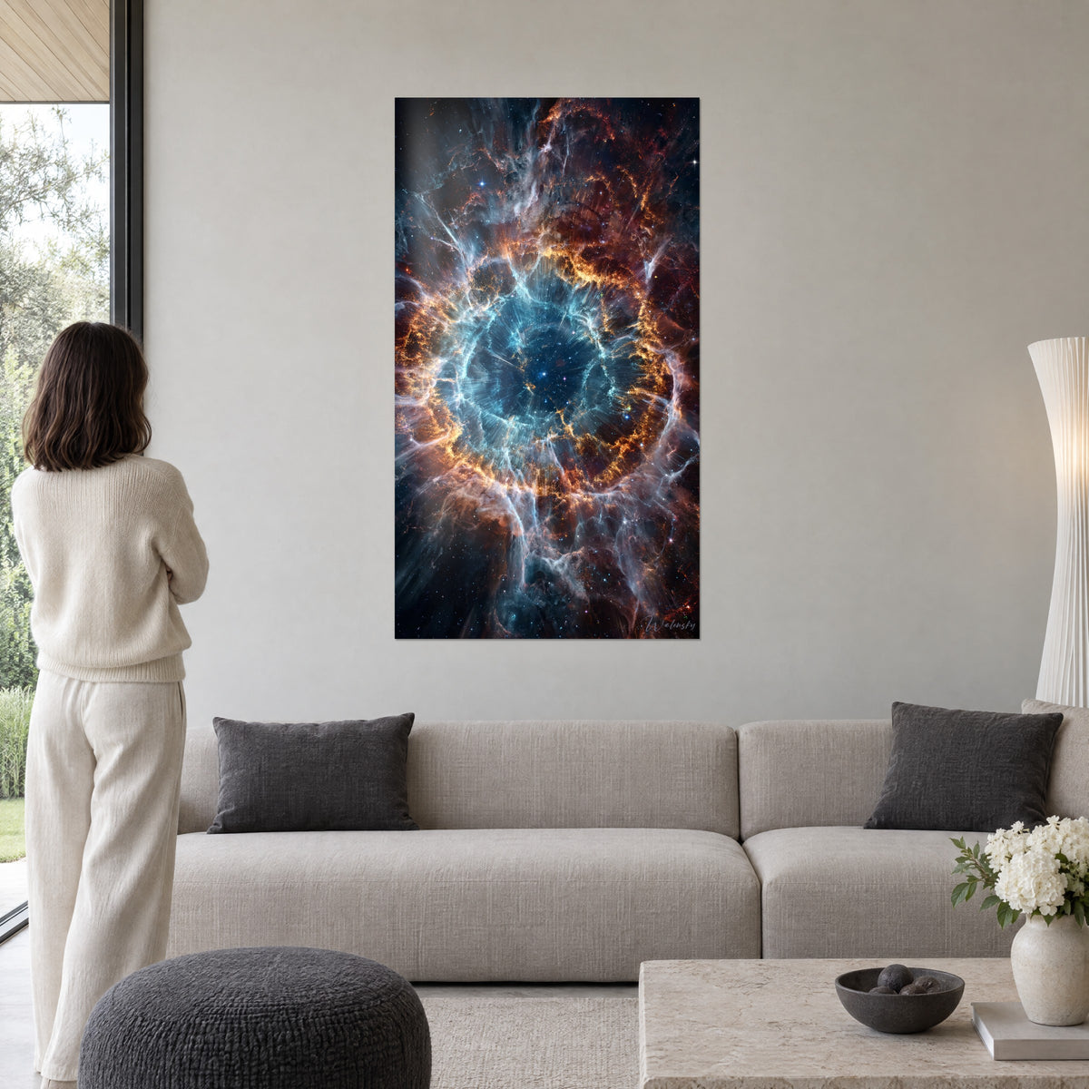 Tableau nébuleuse spiralée aux filaments orange et bleu glacier, observée par une femme de dos, au-dessus d'un canapé dans un salon lumineux