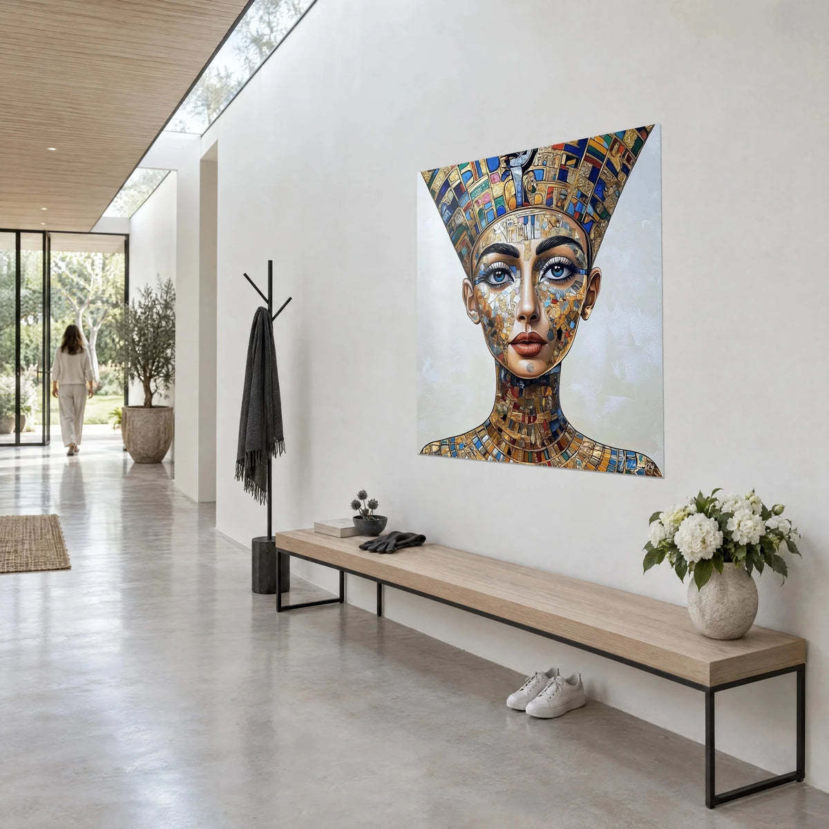 Cuadro Nefertiti de rostro agrietado en oro y cobalto, labios cobrizos, colgado encima de un banco de madera en un pasillo