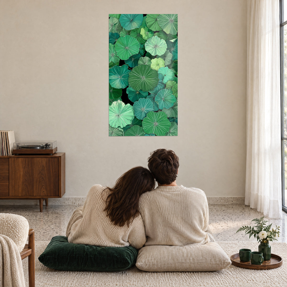 Wall art pond of round leaves in pine green and water green, light veins, two people embracing from behind on cushions in the living room