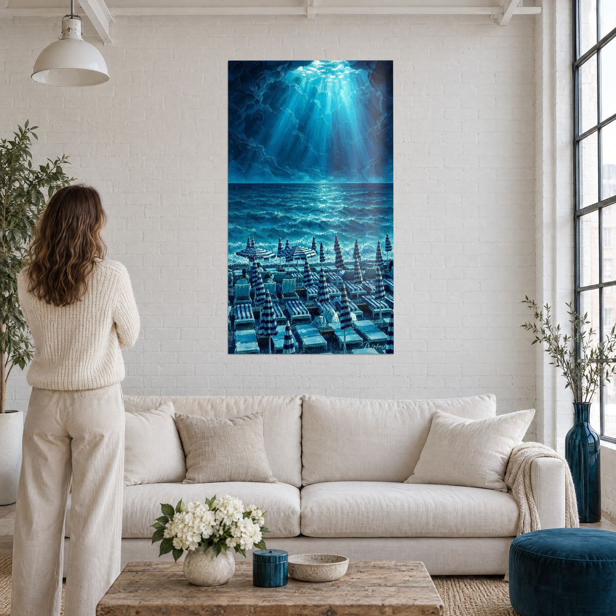 Schilderij strand van Nice onder een bundel turquoise licht, marineblauw gestreepte parasols, boven een bank in een lichte woonkamer