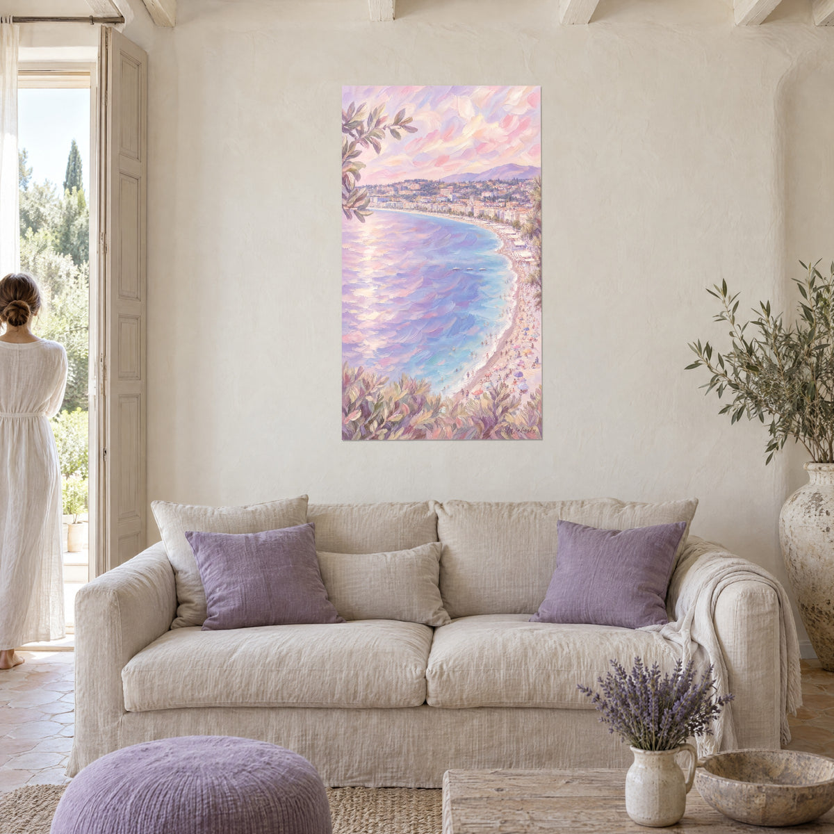 Quadro baia di Nizza dipinta in lilla e rosa, mare blu e spiaggia animata, una donna di spalle, sopra un divano in un soggiorno luminoso