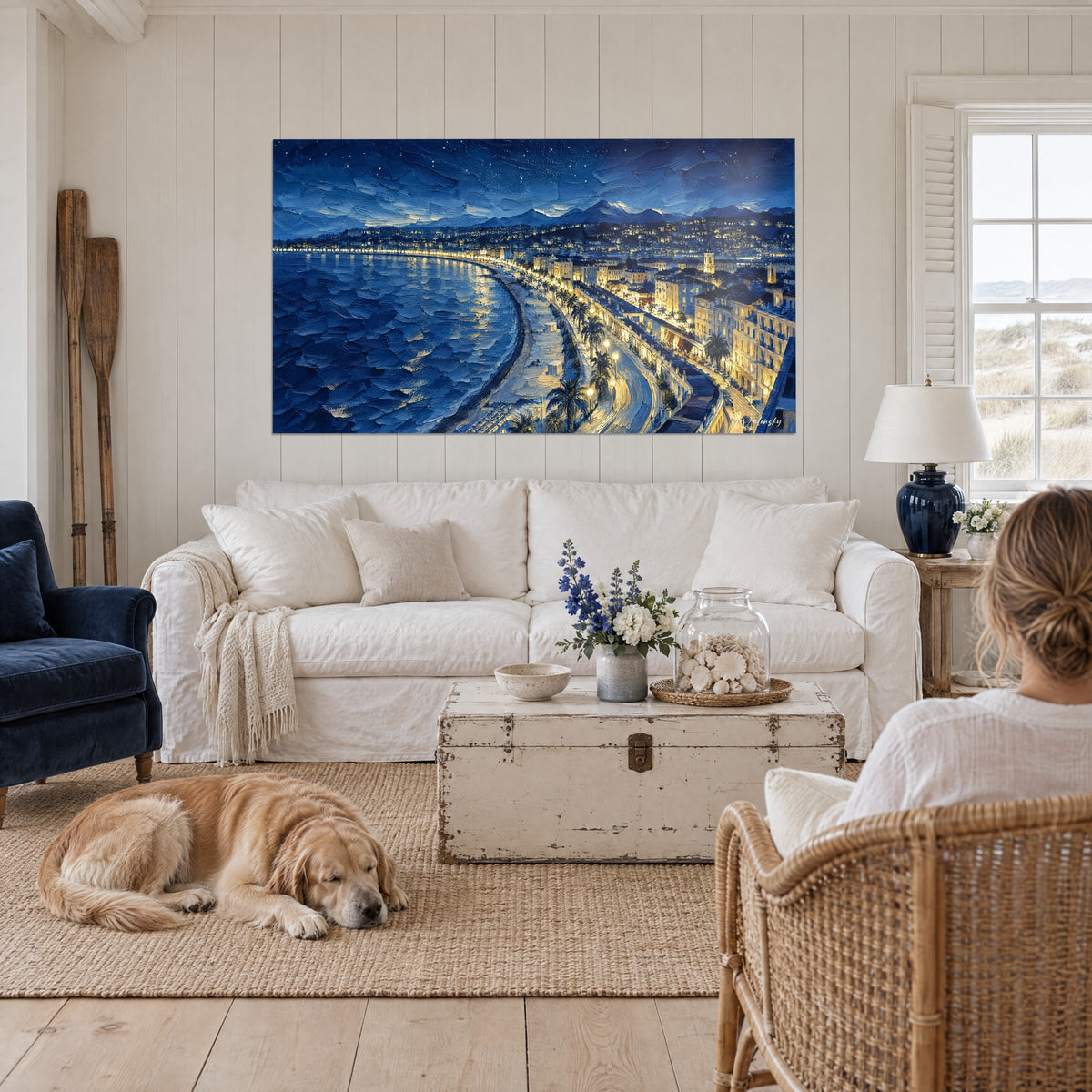 Gemälde Bucht bei Nacht in Nachtblau und Gold, Palmen und beleuchtete Promenade, über einem Sofa in einem hellen Wohnzimmer