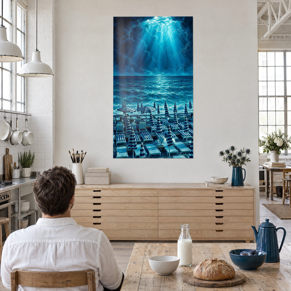 Schilderij kust bij Nice, diep cyaanblauwe golven en bleke lichtstralen die uit een rotsachtige hemel vallen, hangend boven een dressoir van licht hout