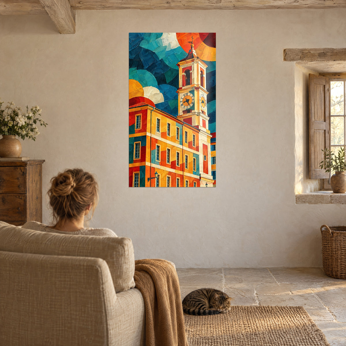Quadro facciata ocra con torretta e sole arancione, donna di spalle su una poltrona e gatto tigrato sdraiato su un tappeto intrecciato