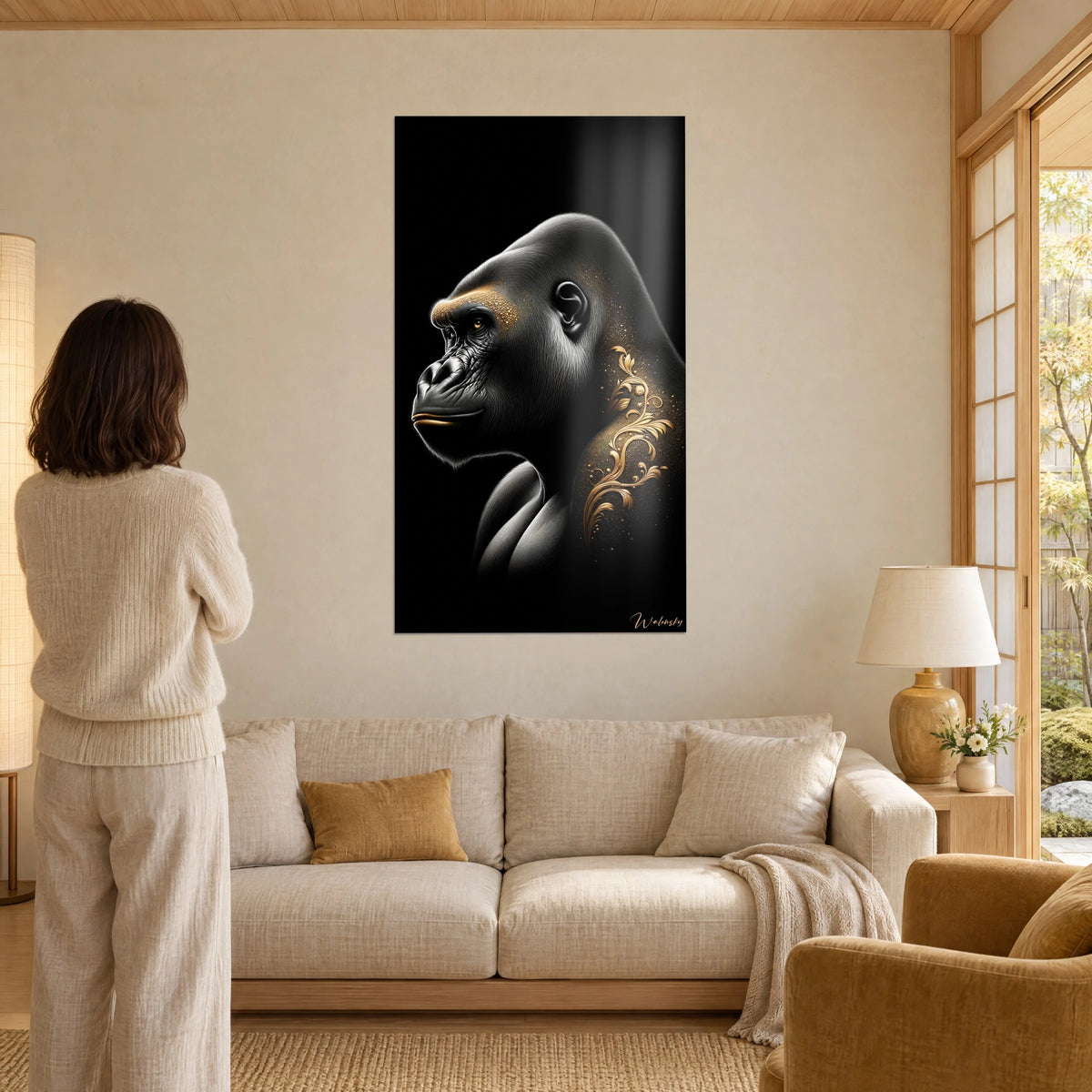 Tableau gorille de profil aux arabesques dorées sur fond noir, femme de dos, au-dessus d'un canapé dans un salon lumineux