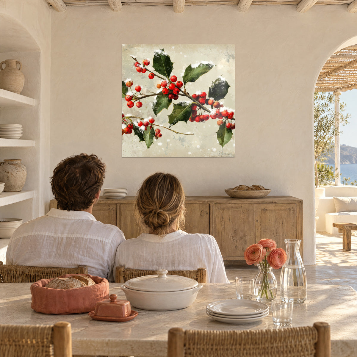 Cuadro acebo navideño con bayas rojo vivo y naranjas sobre fondo beige patinado, pareja de espaldas frente a una mesa de comedor puesta