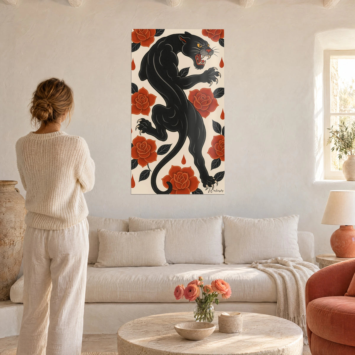 Cuadro de una pantera negra saltando entre rosas rojo anaranjado sobre fondo crema, mujer de espaldas, encima de un sofá en un salón luminoso