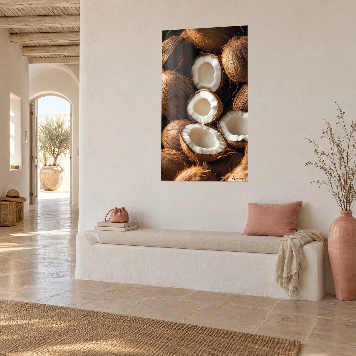 Cuadro de pila de cocos partidos, núcleo marfil y cáscara cobriza, sobre una pared crema junto a un banco blanco y un jarrón rosa