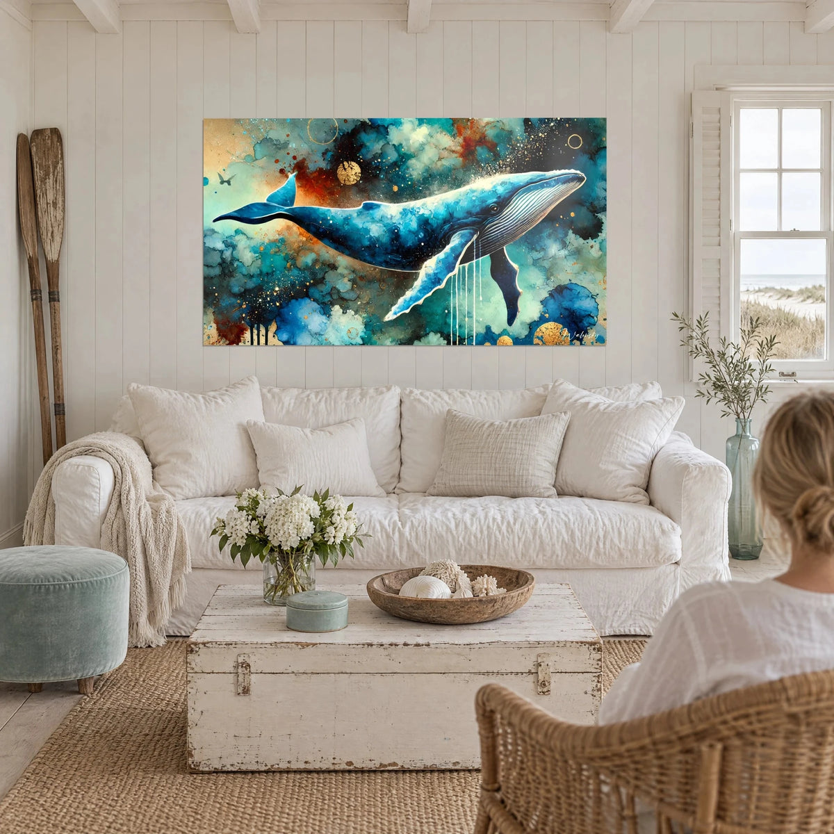 Wall art deep navy whale swimming through turquoise and rust clouds, above a sofa in a bright living room
