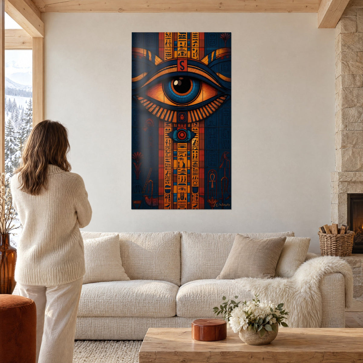 Wall art Eye of Horus outlined in midnight blue and saffron orange, gold hieroglyphs, woman seen from behind above a sofa in a bright living room