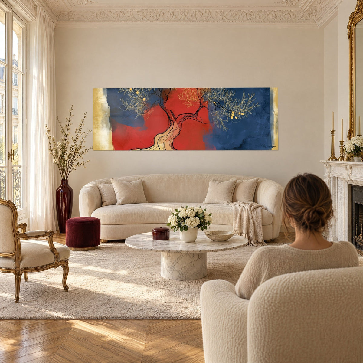 Cuadro de olivo estilizado con ramas doradas sobre fondo rojo vivo y azul noche, encima de un sofá en un salón luminoso