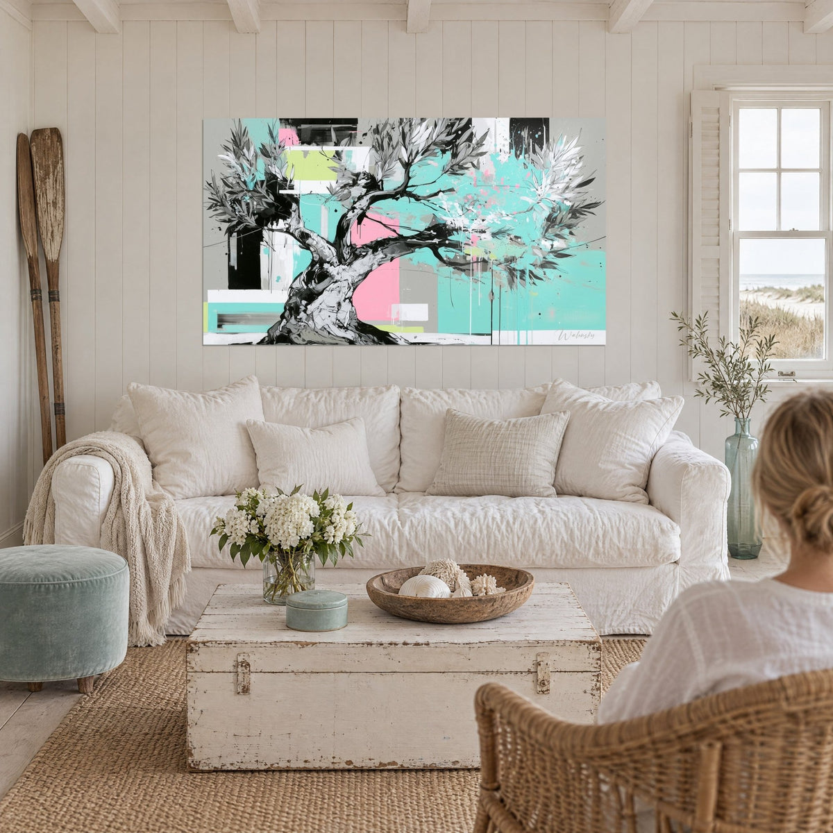 Wall art gnarled olive tree with grey striated trunk and silvery foliage on turquoise background, pale pink, above a sofa in a bright living room