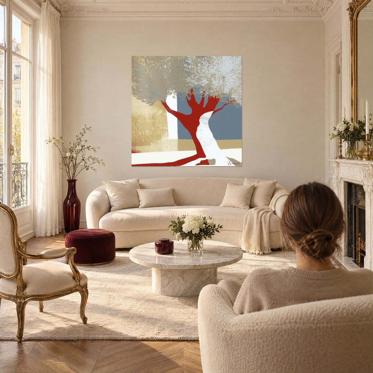Gemälde eines stilisierten Olivenbaums mit ziegelrotem Stamm und silbrigem Laub auf blaugrauem Grund, Frau von hinten, über einem Sofa in einem hellen Wohnzimmer