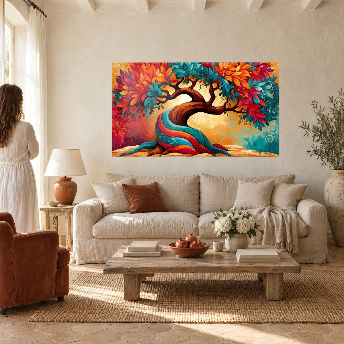 Tableau arbre tourbillonnant aux feuilles turquoise et corail sur fond doré, femme de dos, au-dessus d'un canapé dans un salon lumineux