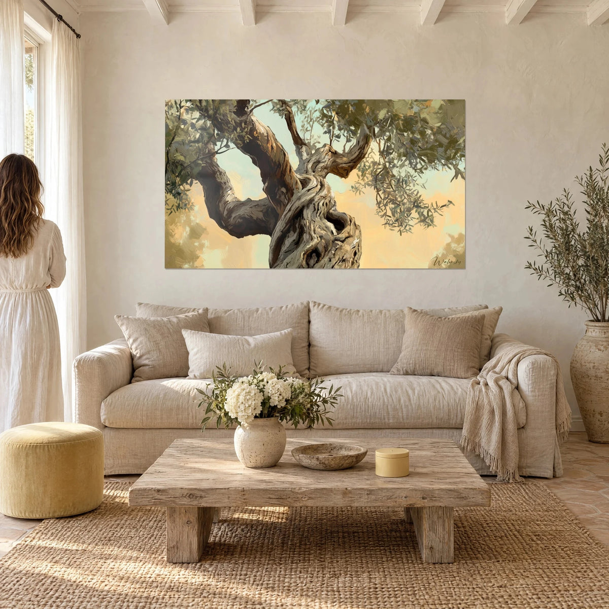 Gemälde Olivenbaum hundertjährig mit knorrigem Stamm, sandgoldener Himmel und graugrünes Laub, über einem Sofa in einem hellen Wohnzimmer