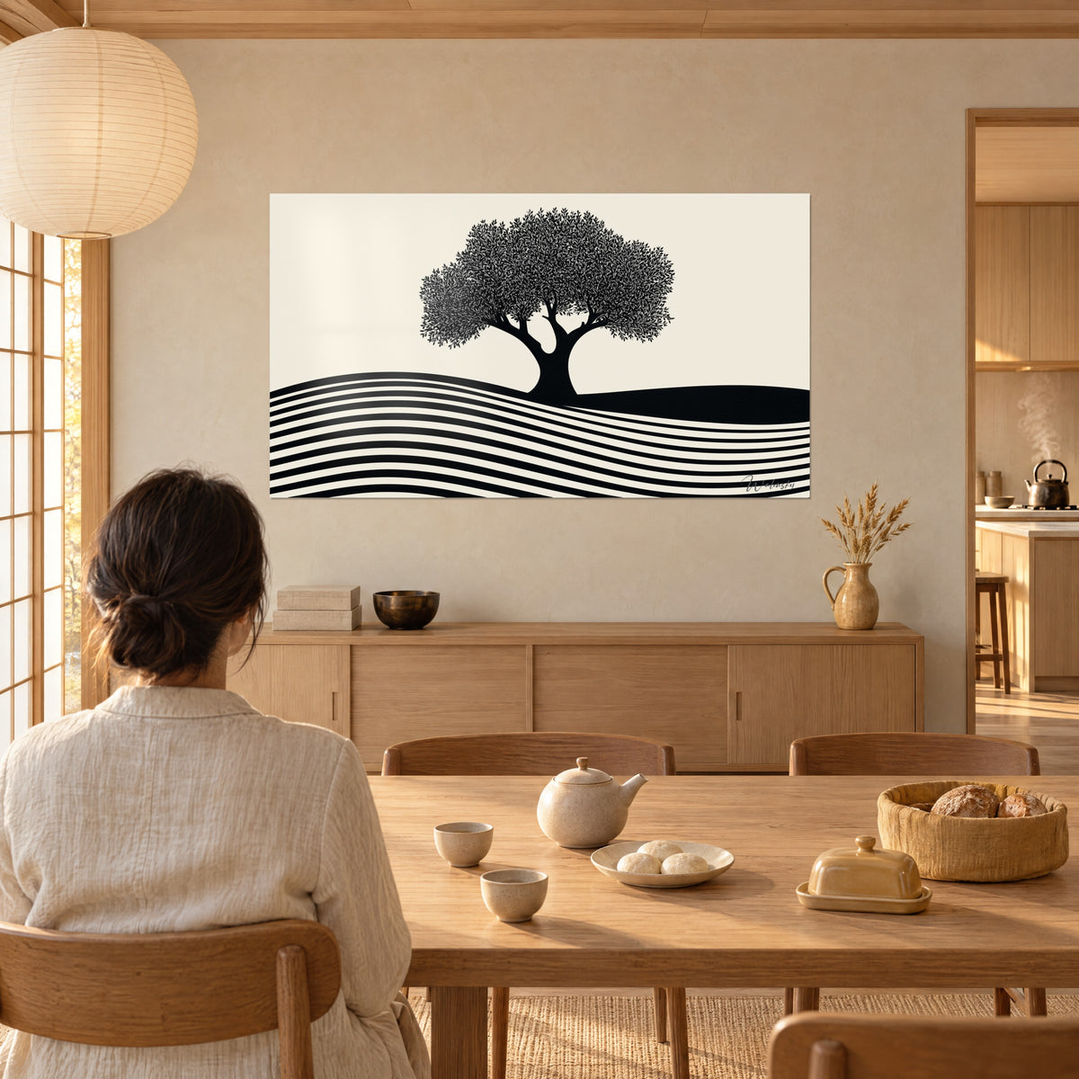 Quadro chioma di ulivo di foglie nere finemente ritagliate su fondo crema, una donna di spalle al tavolo, tè e pane, soggiorno inondato di luce