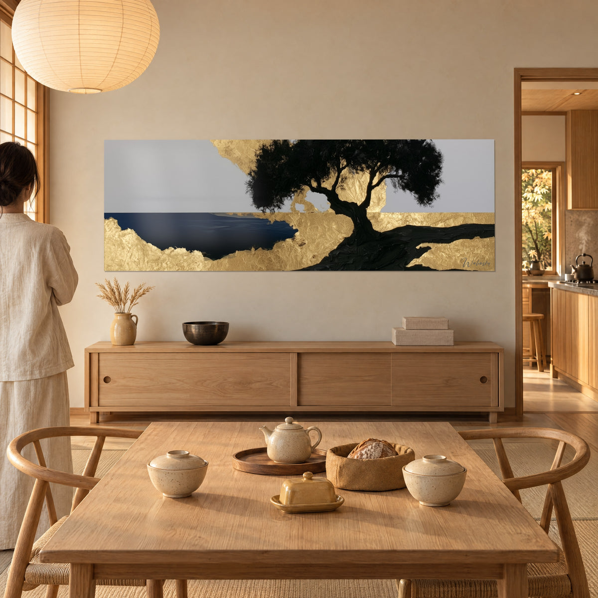 Tableau tronc noir noueux dressé sur rivage doré, mer bleu nuit à gauche, regardé de dos près d'une table en bois clair