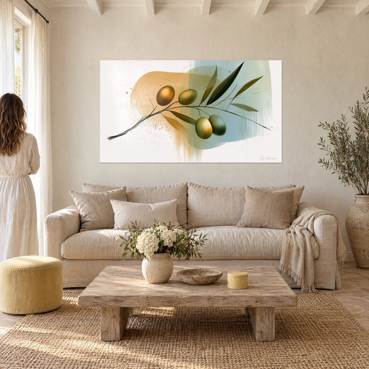 Tableau rameau d'olivier doré aux quatre fruits sur fond ocre et bleu pâle, femme de dos, au-dessus d'un canapé dans un salon lumineux