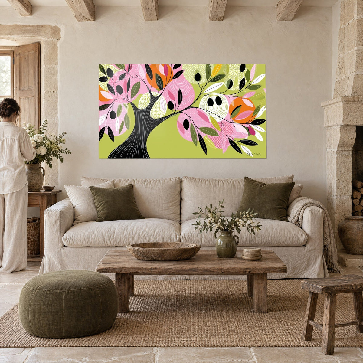 Cuadro olivo estilizado de tronco negro y follaje rosa, fondo verde anís, sobre un sofá en un salón luminoso