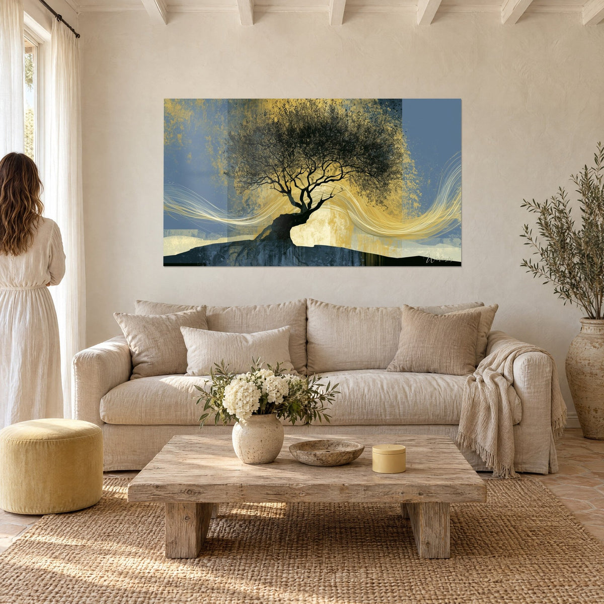 Gemälde Olivenbaum in Schwarz mit dichtem Geäst auf schiefergrauem und goldenem Hintergrund, eine Frau von hinten, über einem Sofa in einem hellen Wohnzimmer
