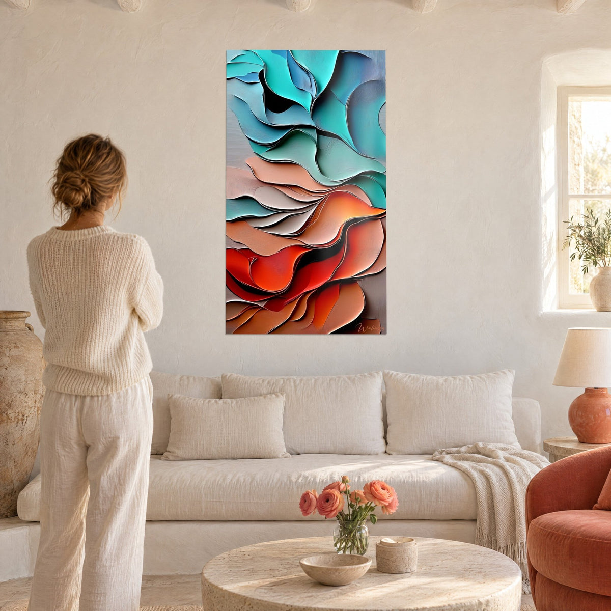 Quadro con onde di carta sovrapposte turchese e rosso corallo, donna di spalle con maglione crema sopra un divano in un soggiorno luminoso