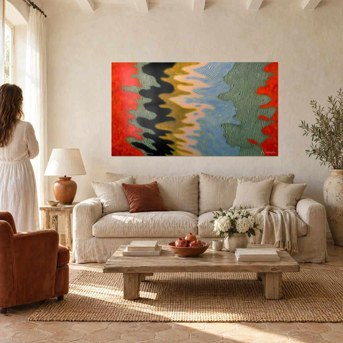 Wall art with wavy stripes in vermilion red and black, cream zebra lines, woman seen from behind, above a sofa in a bright living room