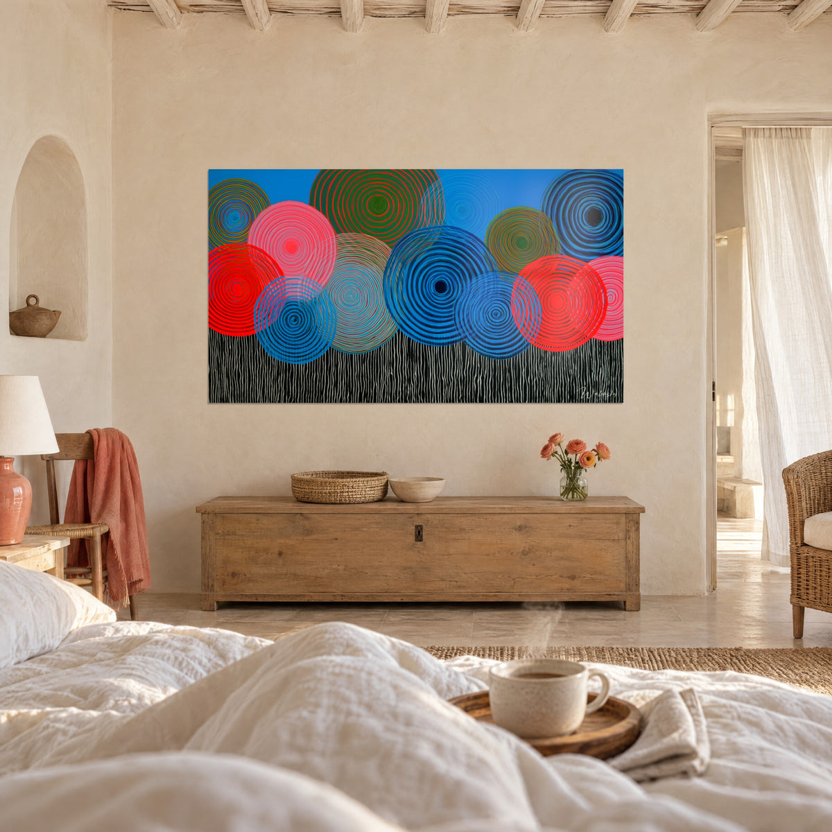 Cuadro con círculos vibrantes bermellón y azul eléctrico sobre un cielo cian, encima de una cama en un dormitorio luminoso