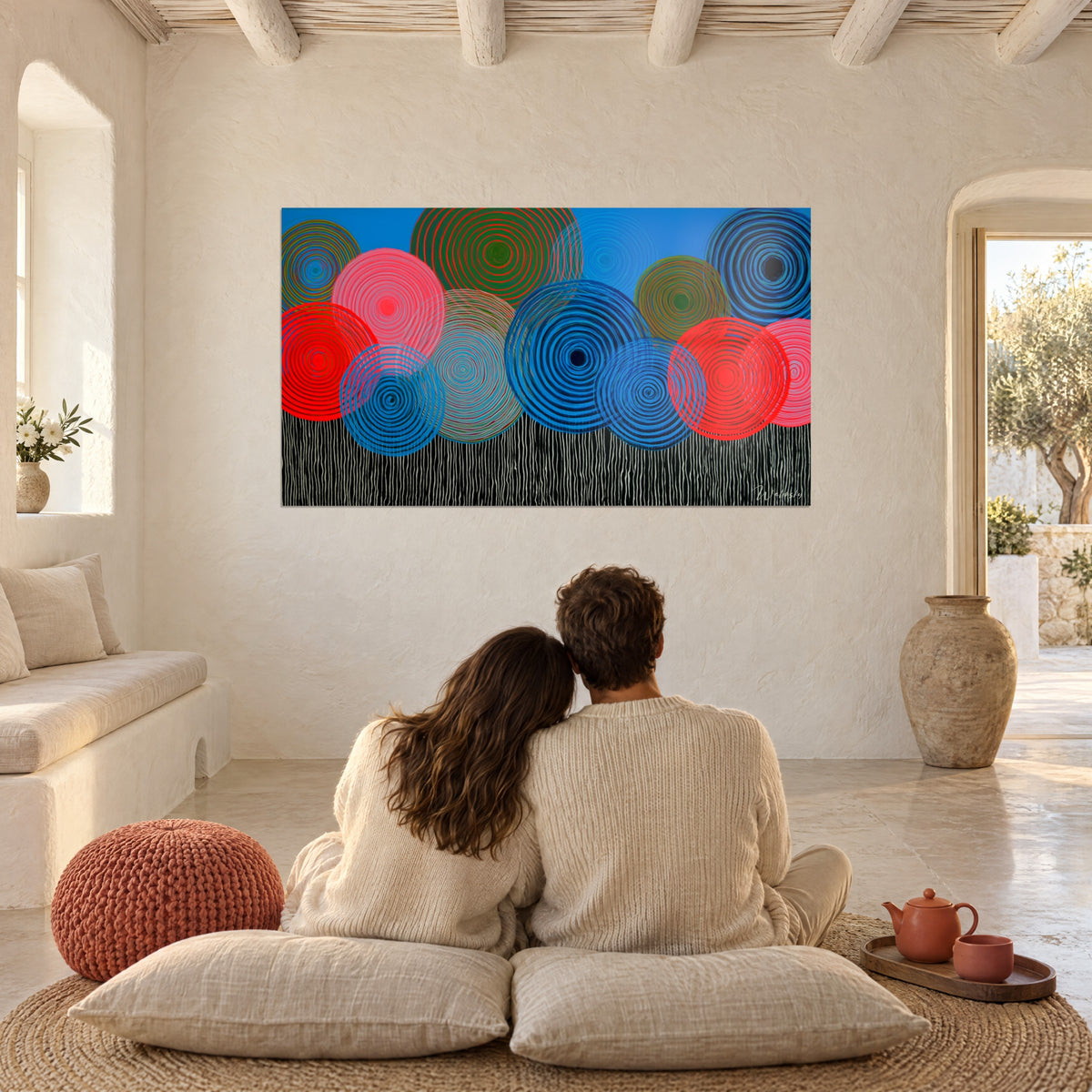 Cuadro con anillos op art rojo fluorescente y azul profundo sobre fondo azur, en un salón de una casa mediterránea
