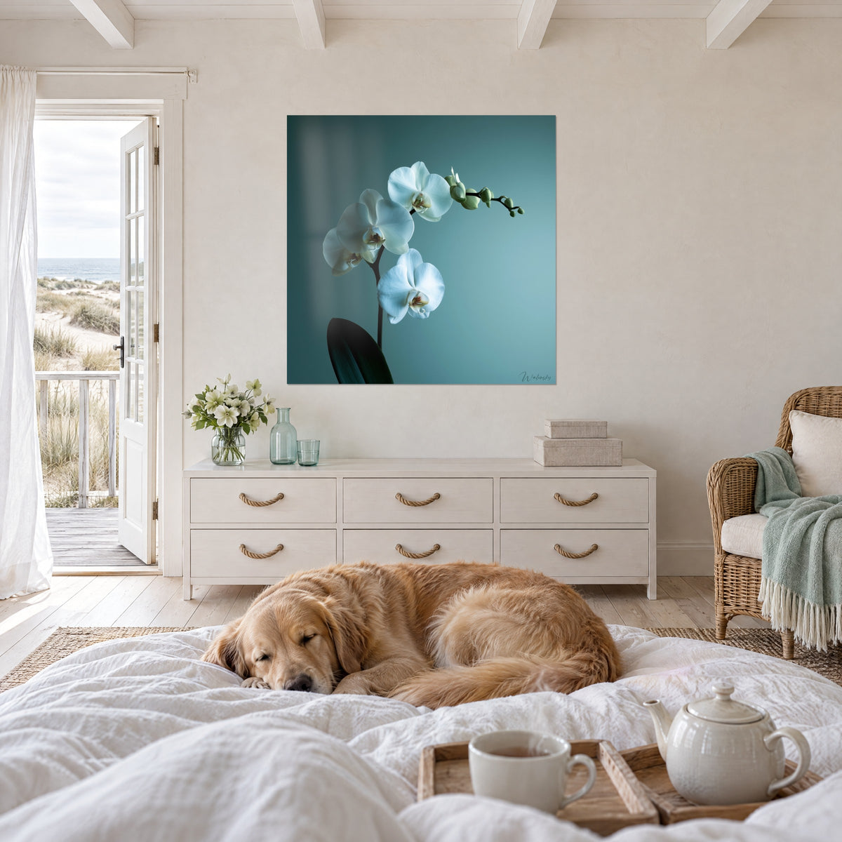 Cuadro vara floral blanca sobre azul petróleo, golden retriever tumbado sobre el edredón, encima de una cama en un dormitorio luminoso
