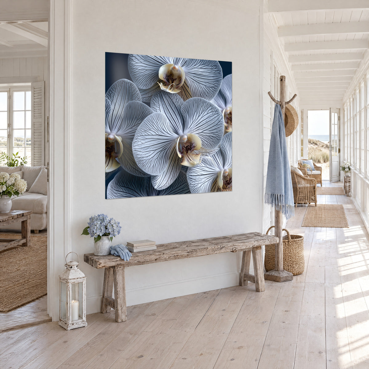 Cuadro de flores de phalaenopsis veteadas de negro, corazón crema y rosa, sobre fondo azul marino, pared blanca de una entrada junto al mar