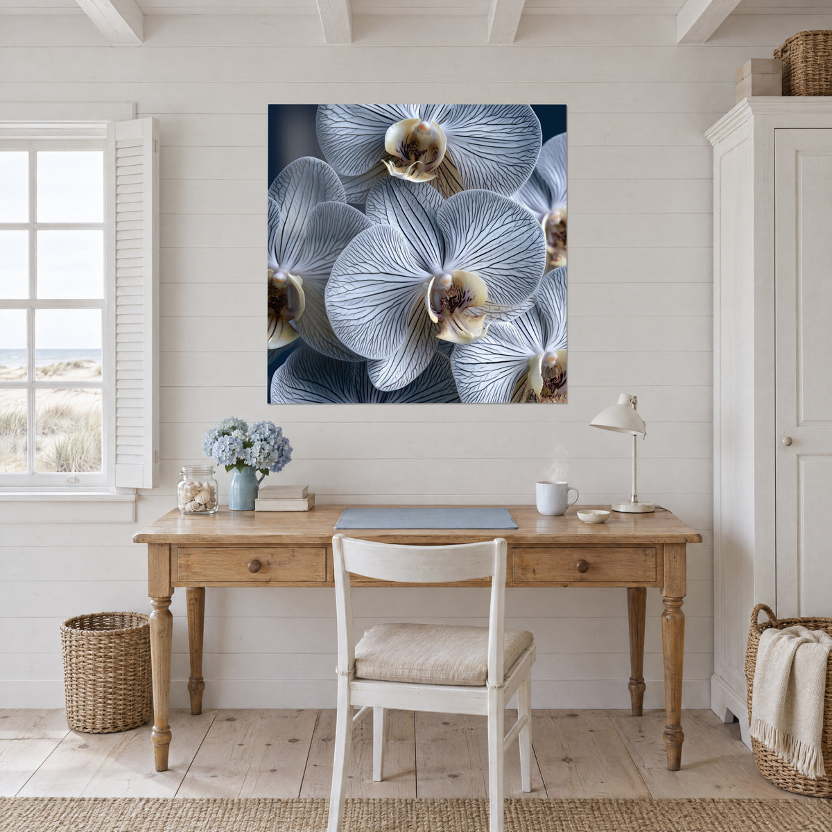 Cuadro de corolas de orquídea blanco azulado nervadas de antracita, labelo crema, pared blanca sobre un escritorio de madera clara