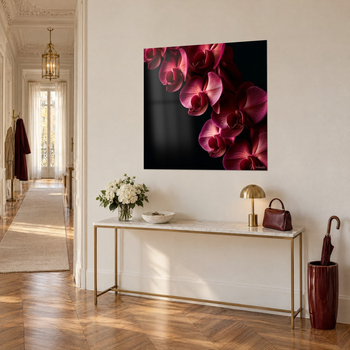 Wall art with a magenta and pale pink orchid branch on deep black, above a gilded console, three-quarter view
