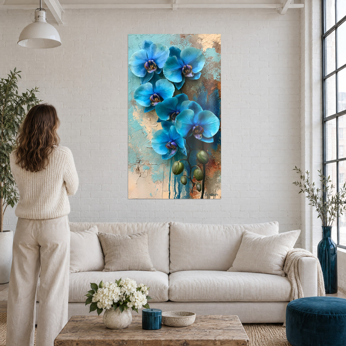 Gemälde mit türkisblauen Orchideen und violetten Herzen auf ockerfarbenem und blaugrünem Grund, Frau von hinten, über einem Sofa in einem hellen Wohnzimmer