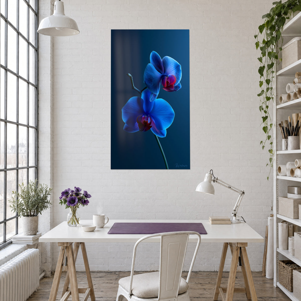 Cuadro tallo de orquídea con pétalos zafiro y corazón carmesí sobre fondo azul petróleo, encima de un escritorio claro junto a un caballete