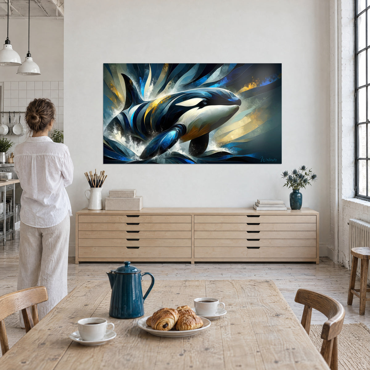 Tableau grand dauphin noir et blanc bondissant, écume blanche et lames bleu roi, une femme de dos devant le mur du loft