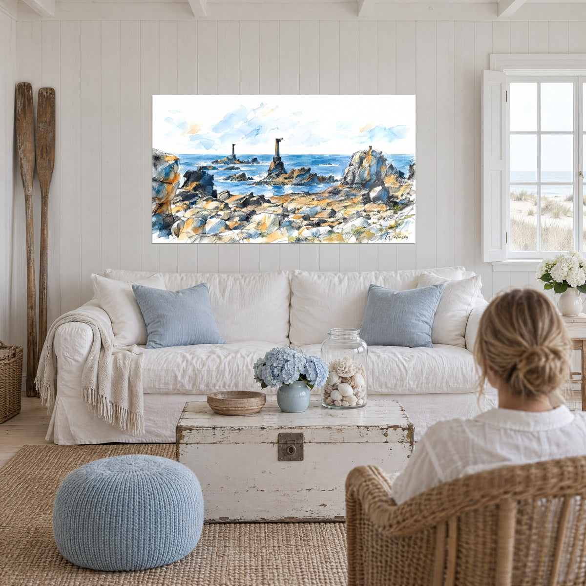 Tableau phares d'Ouessant sur mer bleue, rochers ocre et ciel pâle, au-dessus d'un canapé dans un salon lumineux