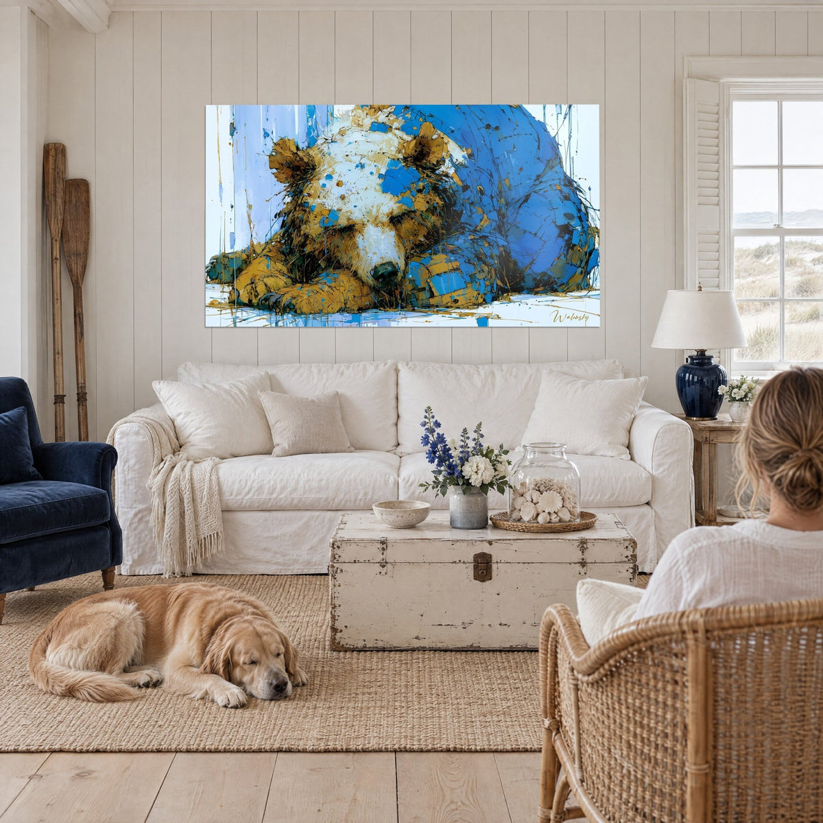Quadro orso bruno addormentato in pennellate a coltello blu cobalto e ocra dorata, golden retriever disteso ai piedi del divano, appeso sopra un divano in un soggiorno luminoso