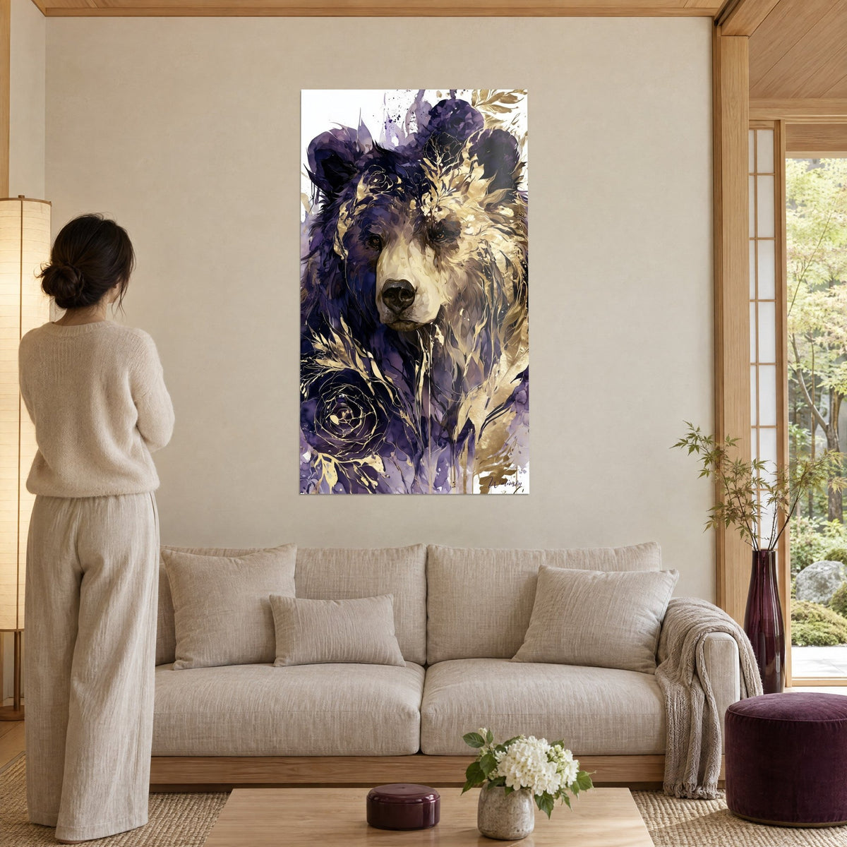 Gemälde Bär in Violett mit goldenem Fell, Indigoblüten und Goldblättern, Frau von hinten über einem Sofa in einem hellen Wohnzimmer