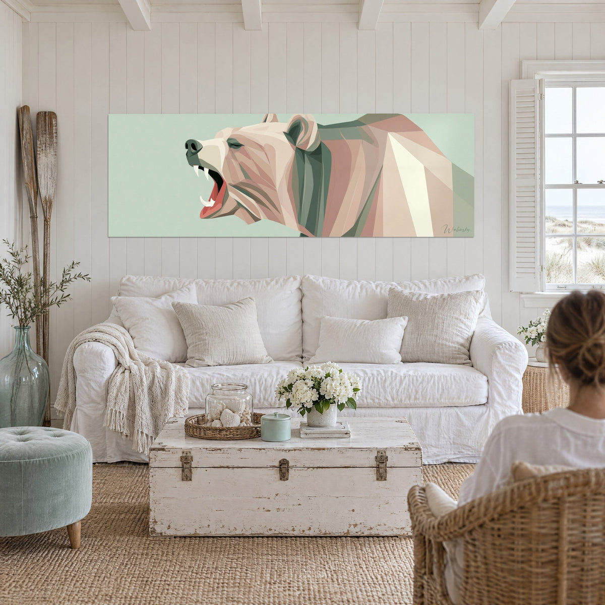 Quadro di un orso bruno geometrico che ruggisce in rosa cipria e verde salvia, due persone di spalle, sopra un divano in un soggiorno luminoso