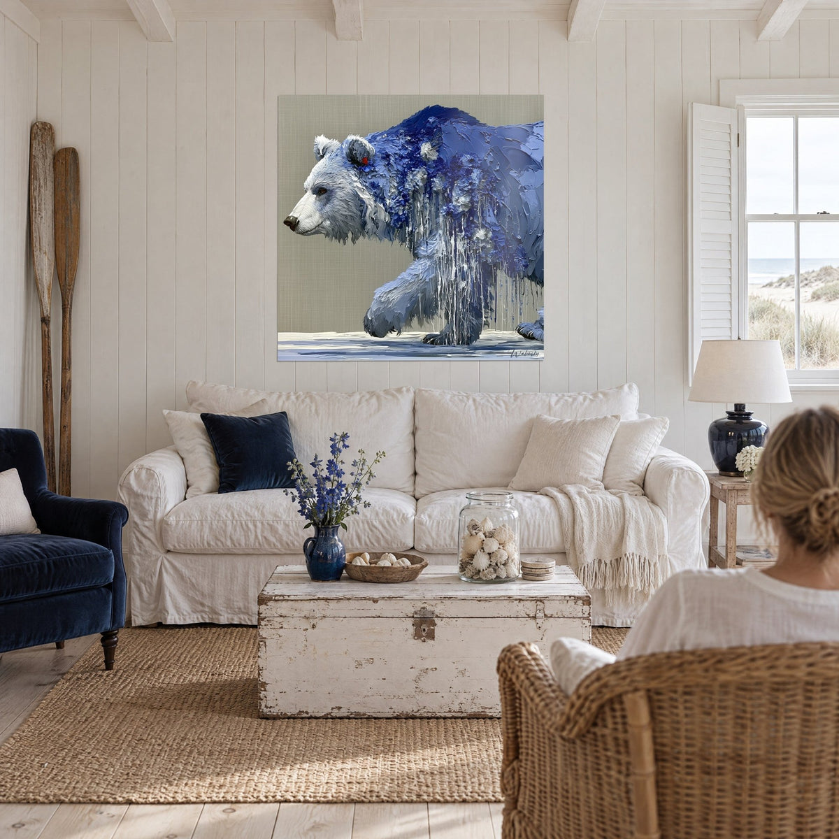 Cuadro oso macizo en pasta azul marino y blanca, goteos verticales sobre fondo gris pardo, encima de un sofá en un salón luminoso