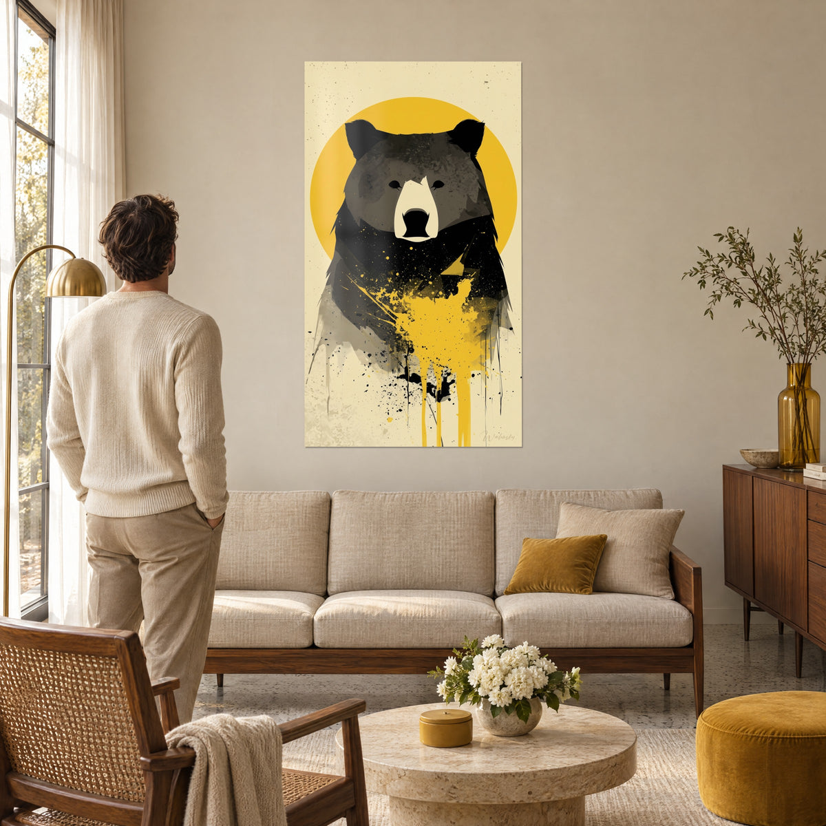 Quadro orso massiccio nero e grigio su disco giallo senape, sfondo crema, uomo di spalle, sopra un divano in un soggiorno luminoso