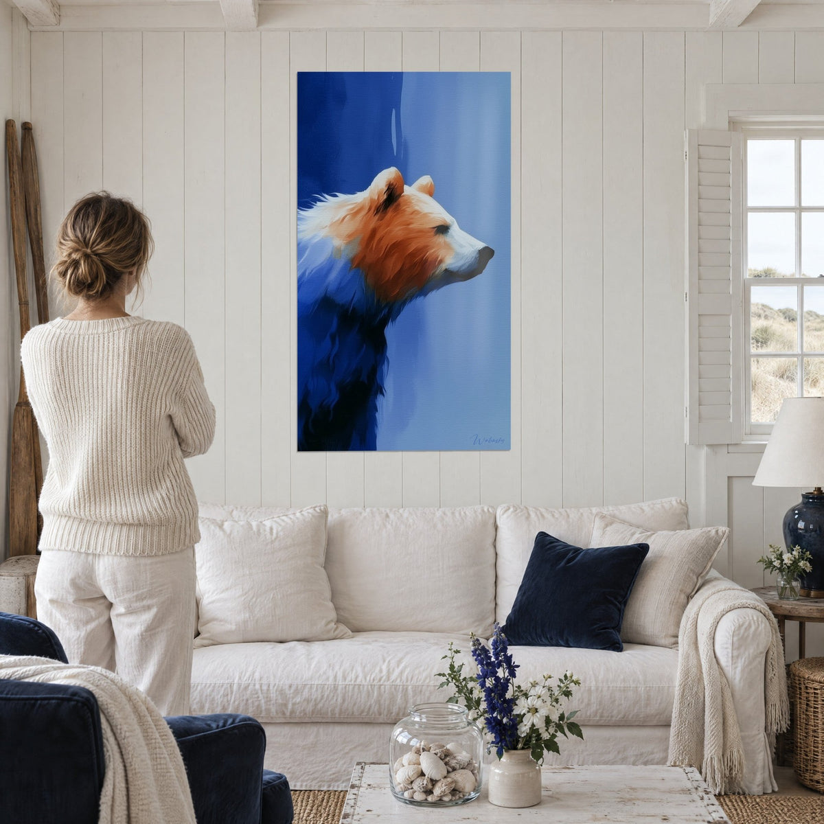 Quadro orso bruno di profilo, pelo ocra e muso bianco su sfondo blu navy, sopra un divano in un soggiorno luminoso